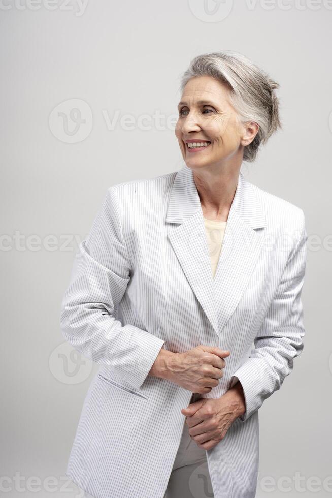 Portrait of happy beautiful senior woman wearing stylish suit, successful businesswoman looking away photo