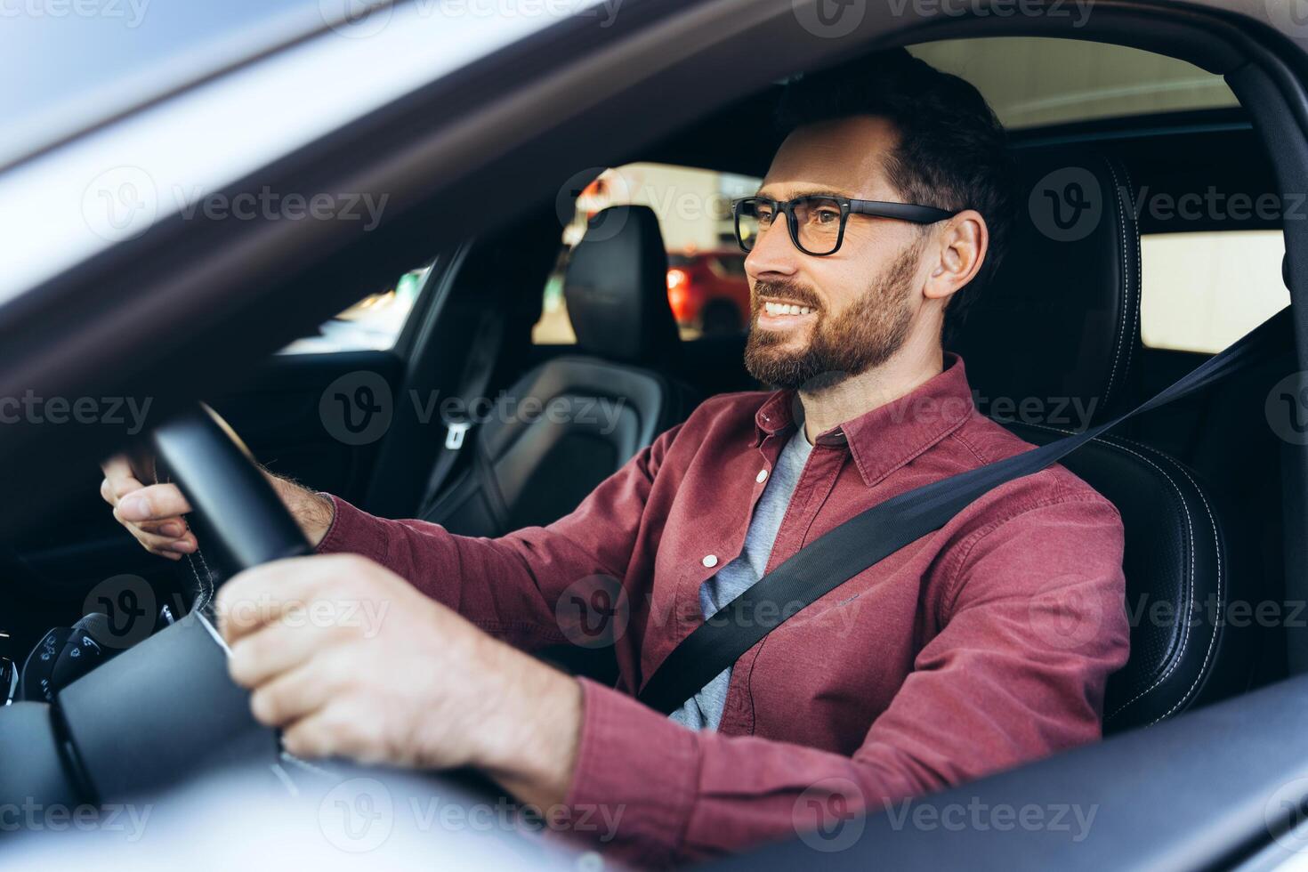 Portrait of smiling, confident bearded man, driver, wearing eyeglasses driving car, looking away photo