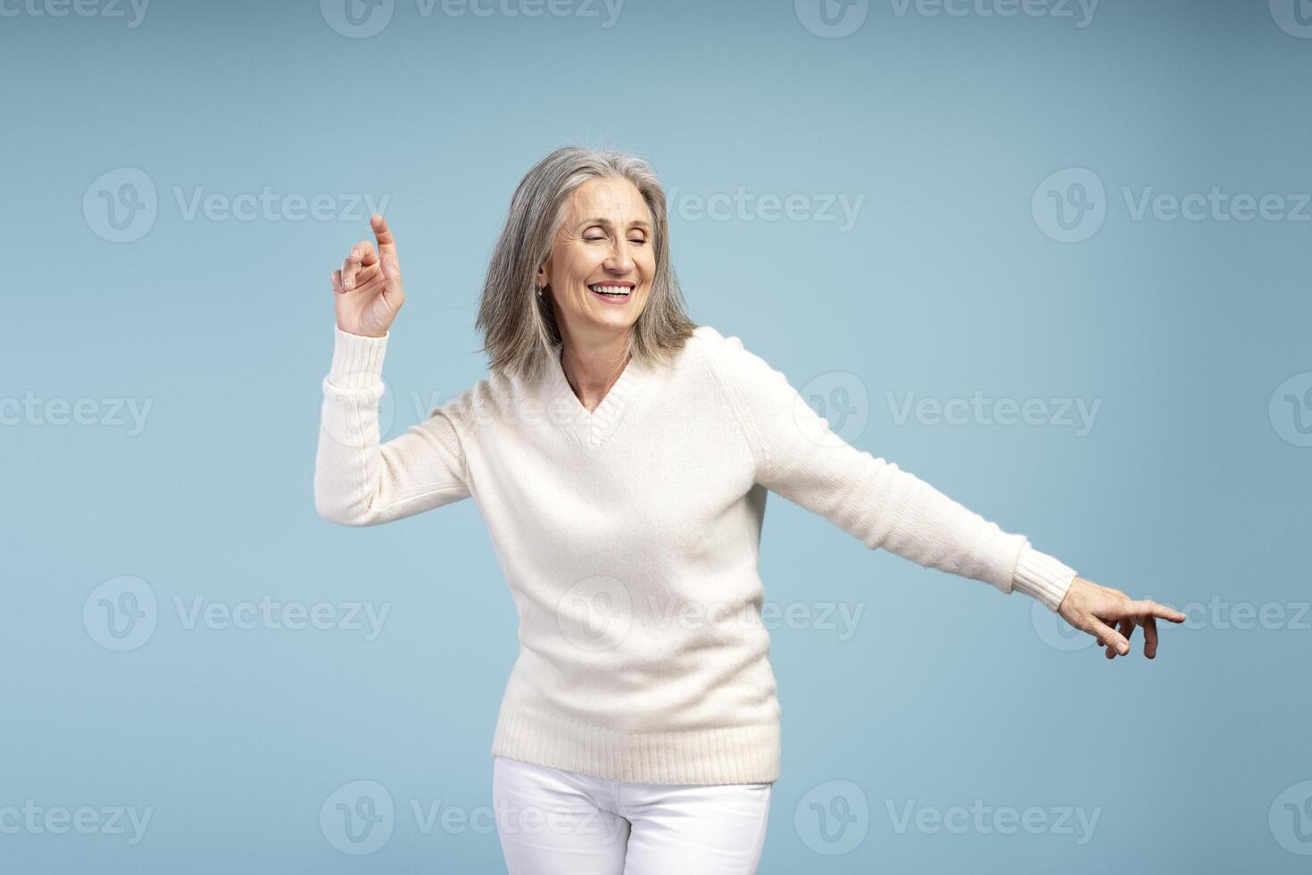 Portrait of happy, smiling mature woman with closed eyes, dancing, having fun photo