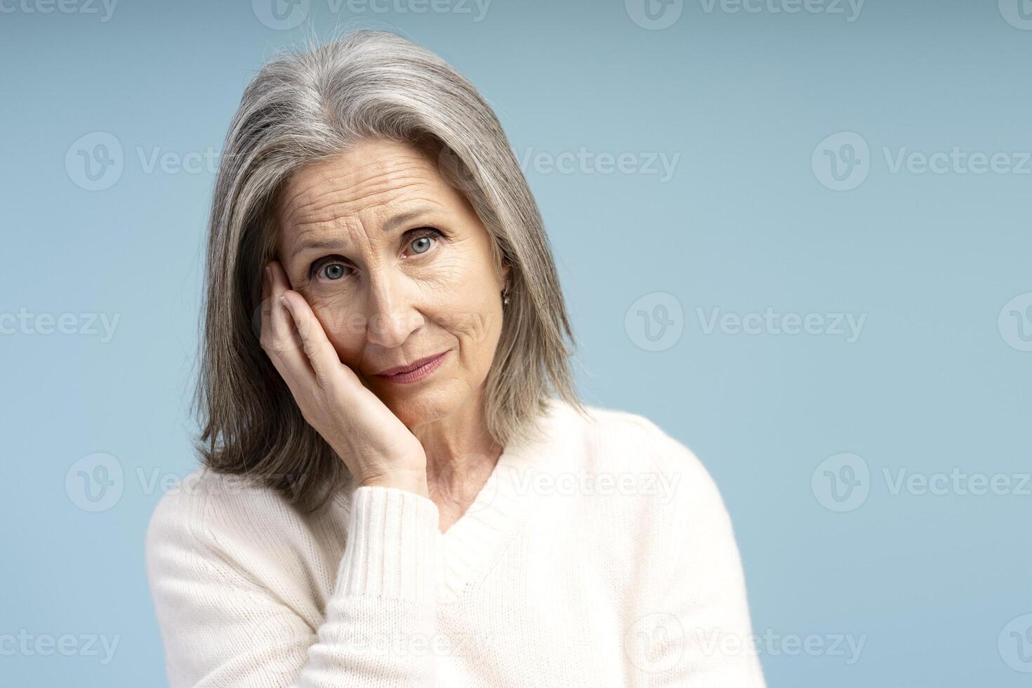 Portrait of pensive, tired, gray haired senior woman looking at camera, copy space photo