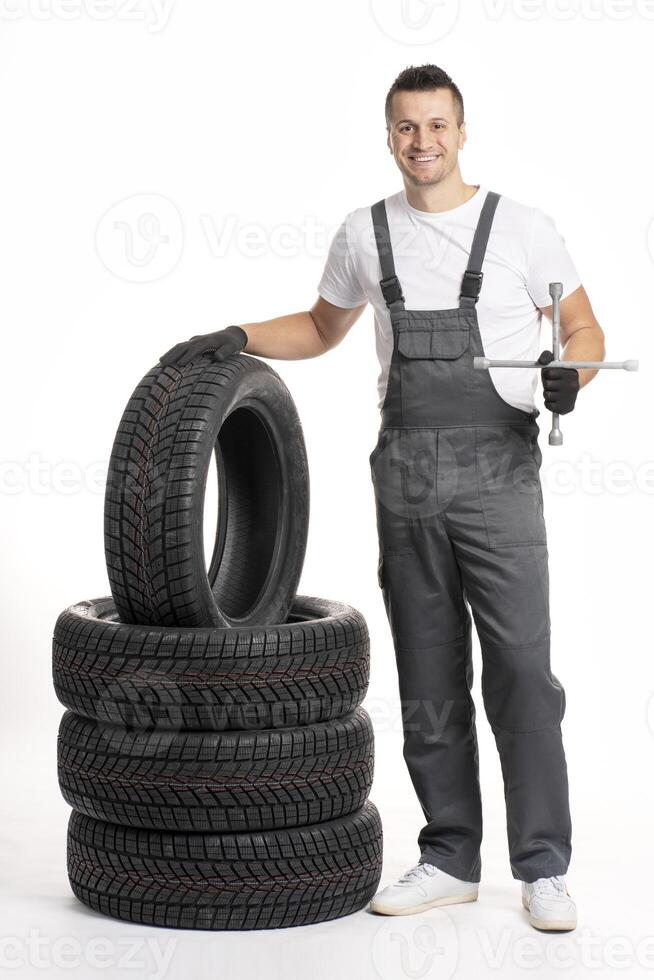 Mechanic holding lug wrench and leaning on stack of tires photo
