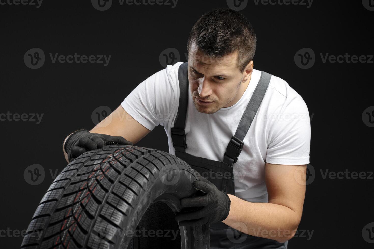Mechanic inspecting winter tire tread depth on black background photo
