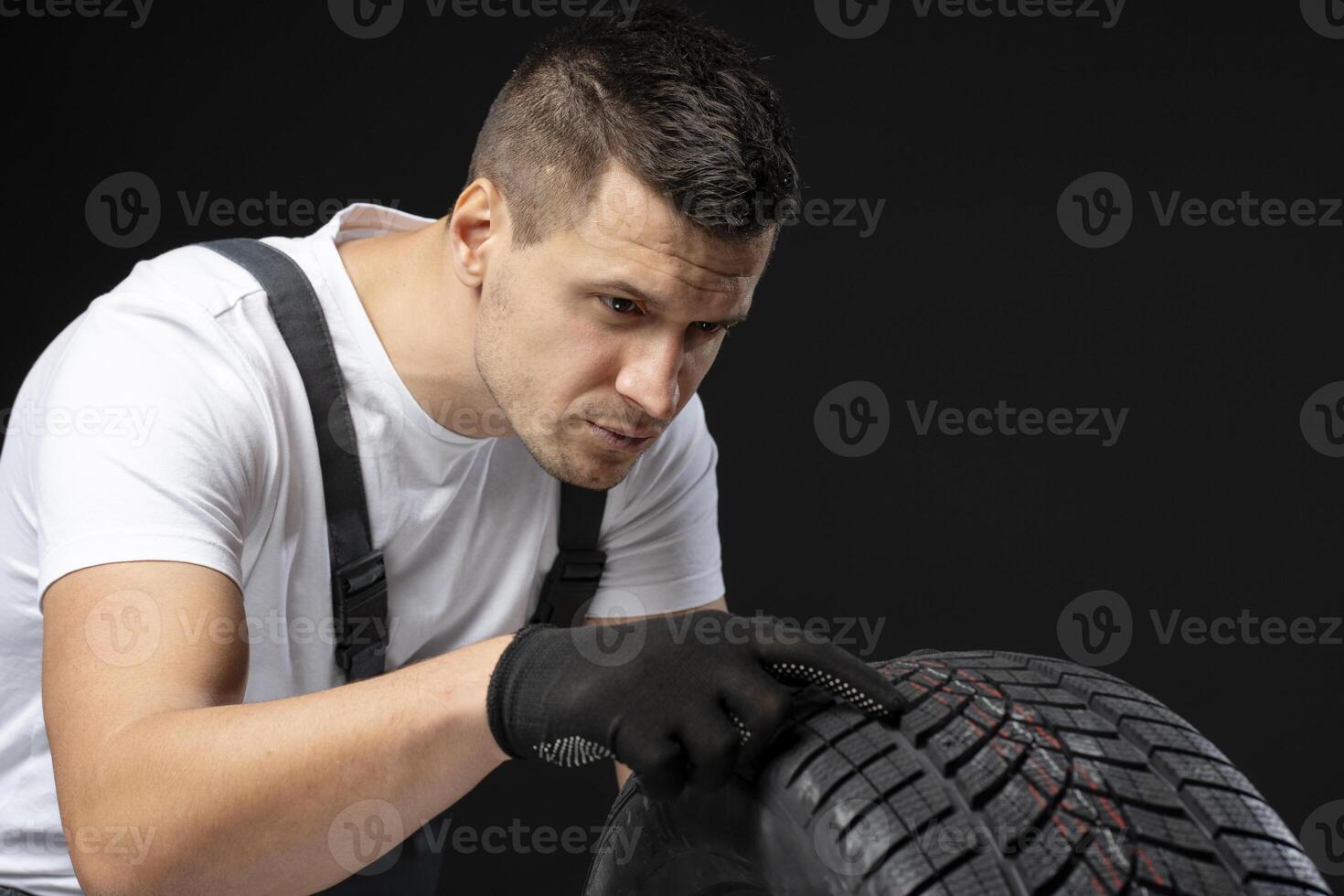 Mechanic inspecting winter car tire tread depth on black background photo