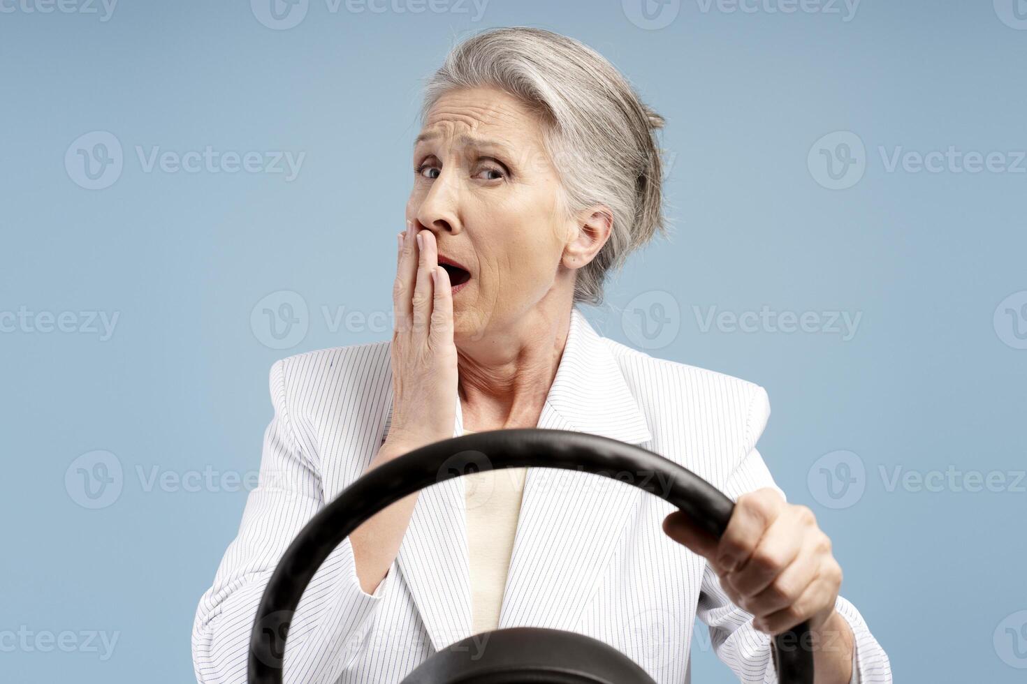 Portrait of tired senior woman, driver, holding steering wheel, yawning, looking at camera photo