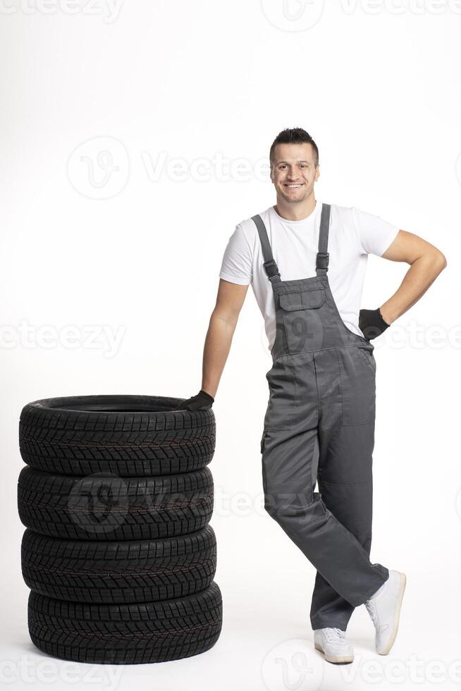 Mechanic leaning on stack of car tires smiling at work photo