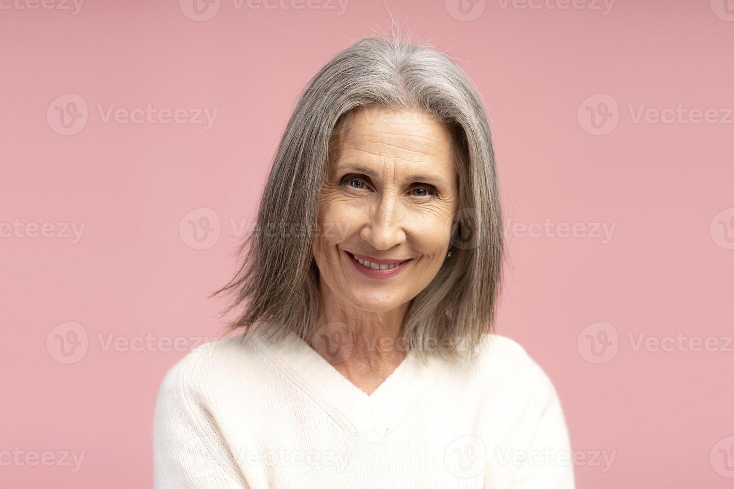 Closeup smiling, beautiful, senior gray haired woman, looking at camera, isolated on pink background photo