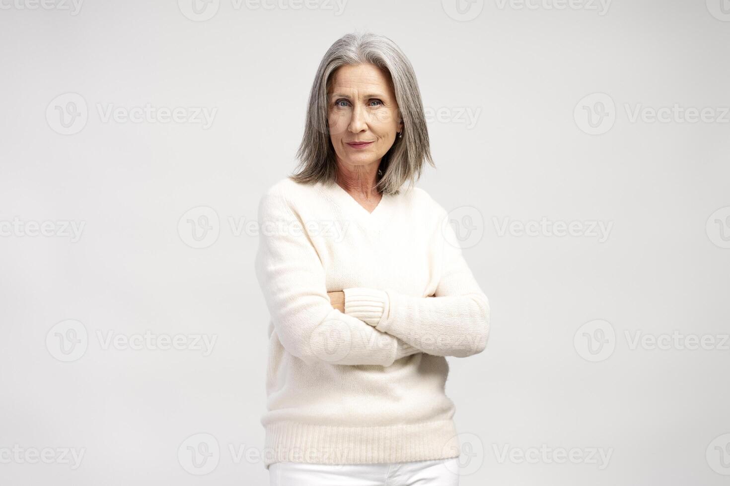 Pensive, serious gray haired senior woman with crossed arms posing isolated on white background photo