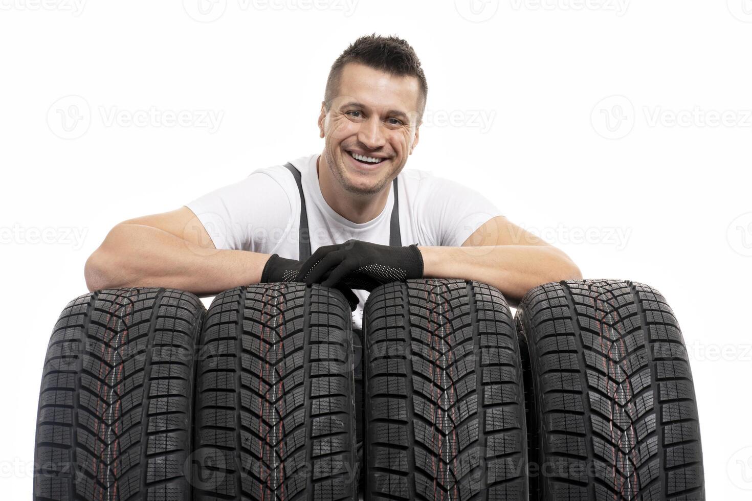 Mechanic leaning on winter tires smiling at auto repair shop photo