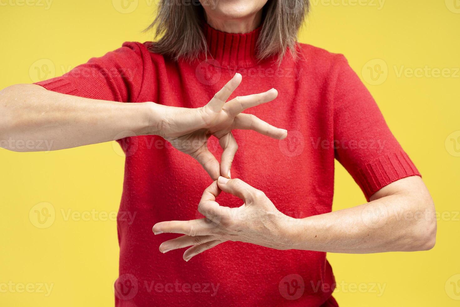 Portrait of senior woman wearing stylish red sweater, gesturing, showing symbols with fingers photo