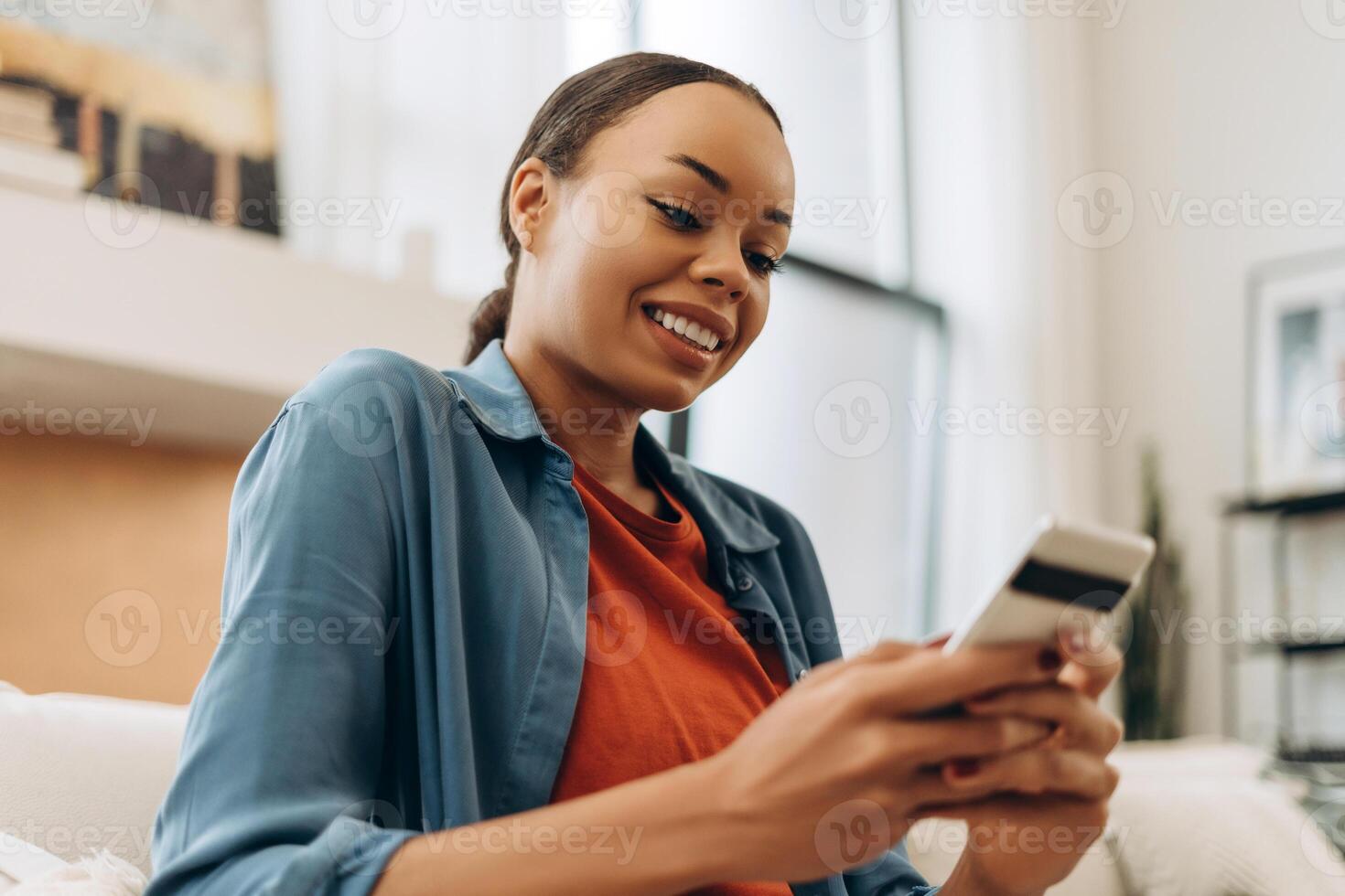 Portrait of beautiful smiling African American young woman holding mobile phone, using mobile app photo