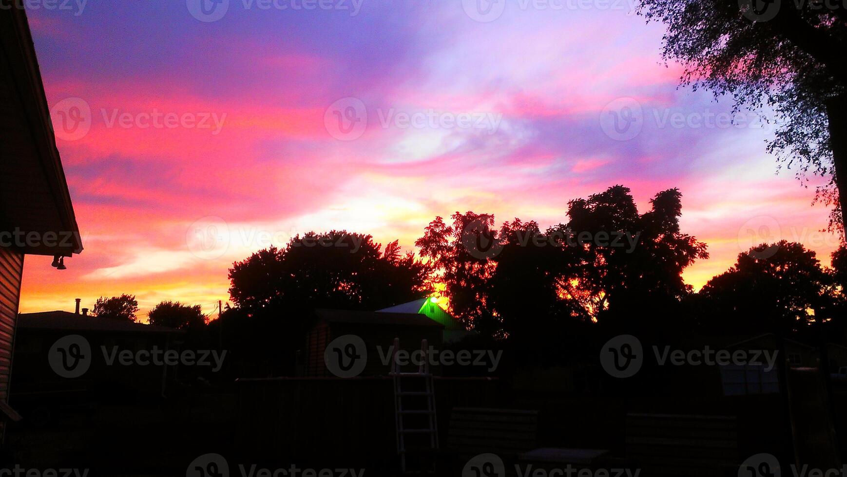 A colorful sunset over a backyard with a ladder photo