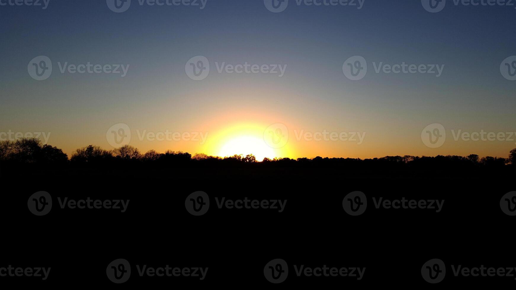 The sun setting over a field photo