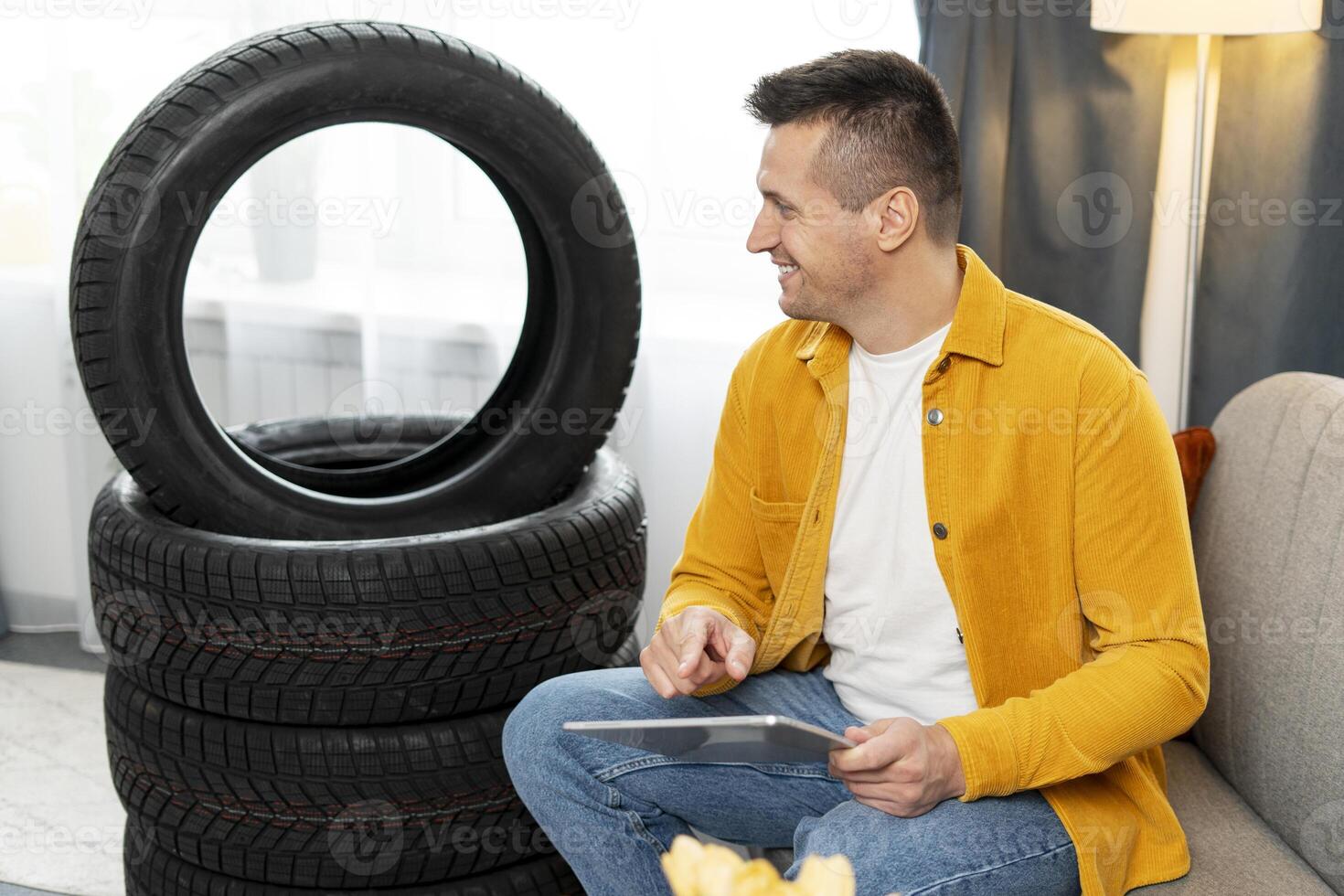 Mechanic browsing tablet next to winter tires at home photo