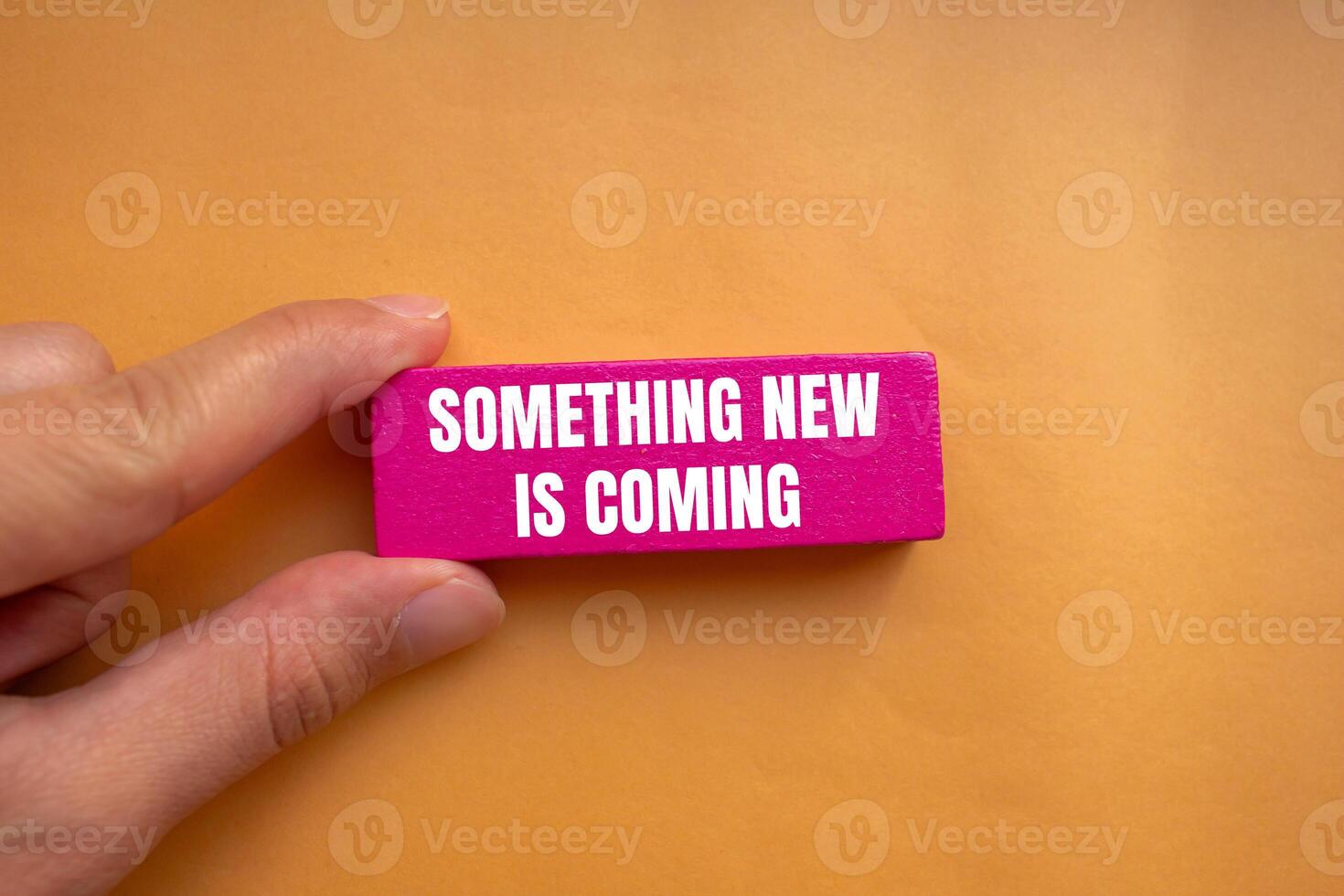 Something new is coming message written on pink wooden block with orange background. Conceptual something new is coming symbol. Copy space. photo