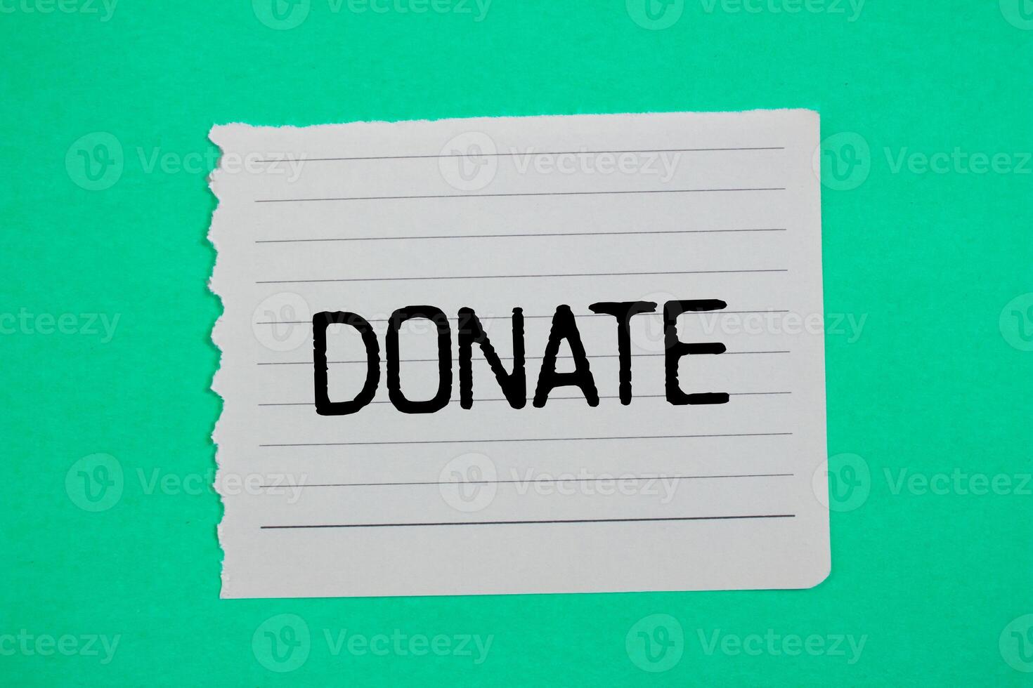 Donate message written on ripped torn paper piece with green background. Conceptual donate symbol. Copy space. photo