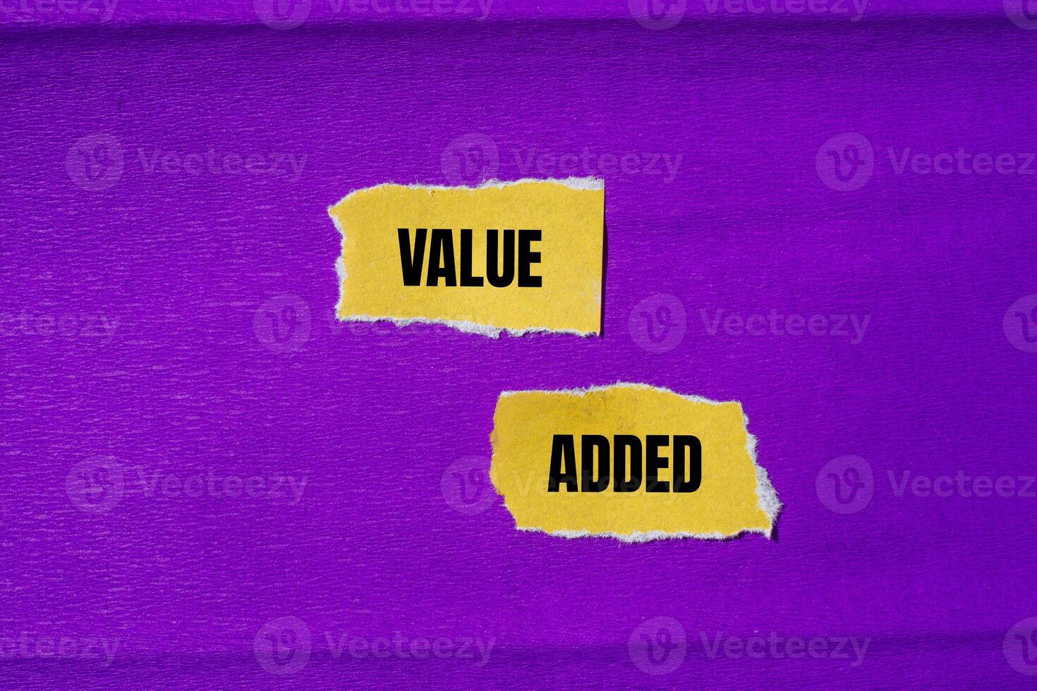 Value added message written on ripped torn yellow paper pieces with purple background. Conceptual value added symbol. Copy space. photo