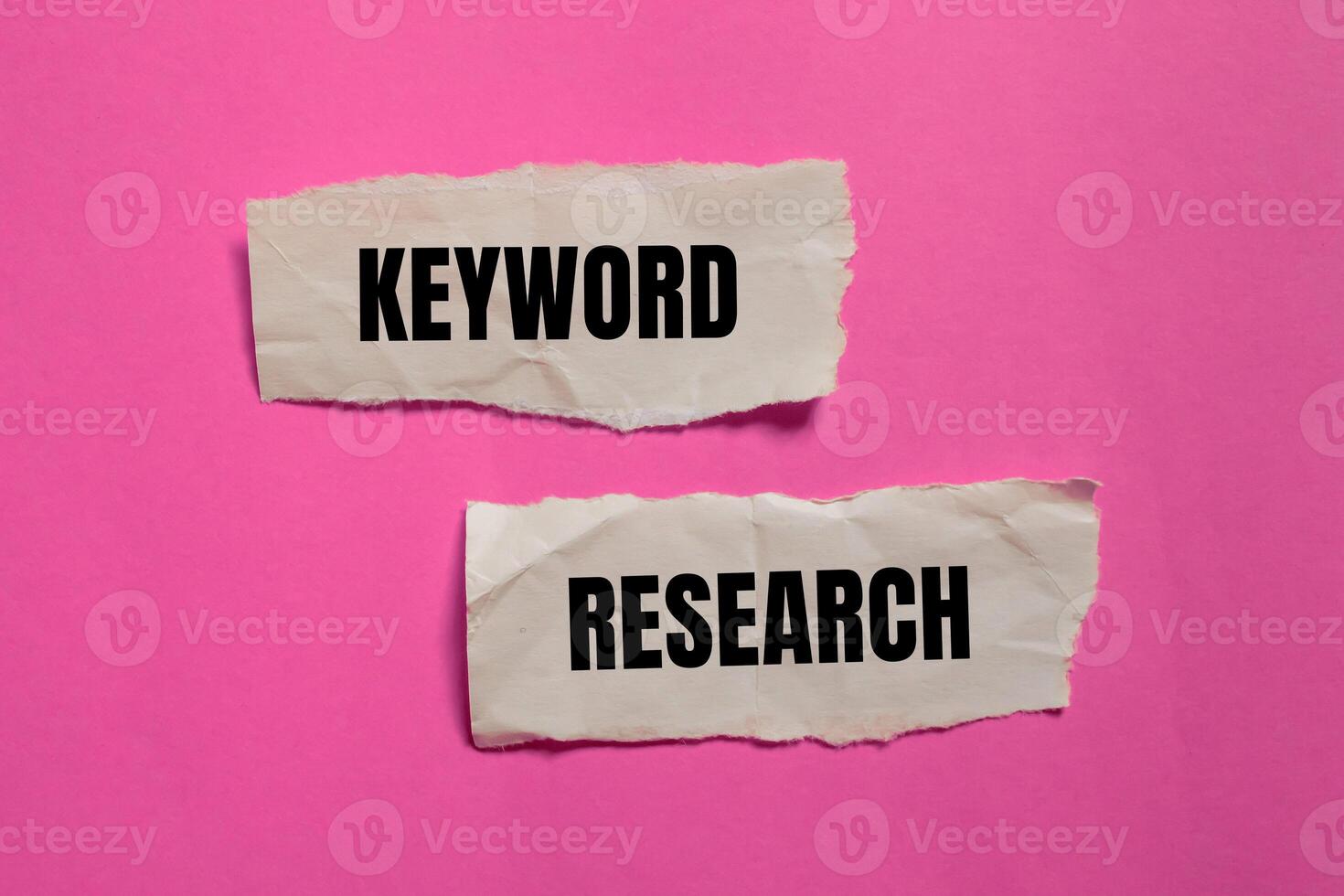 Keyword research message written on ripped paper pieces with pink background. Conceptual keyword research symbol. Copy space. photo