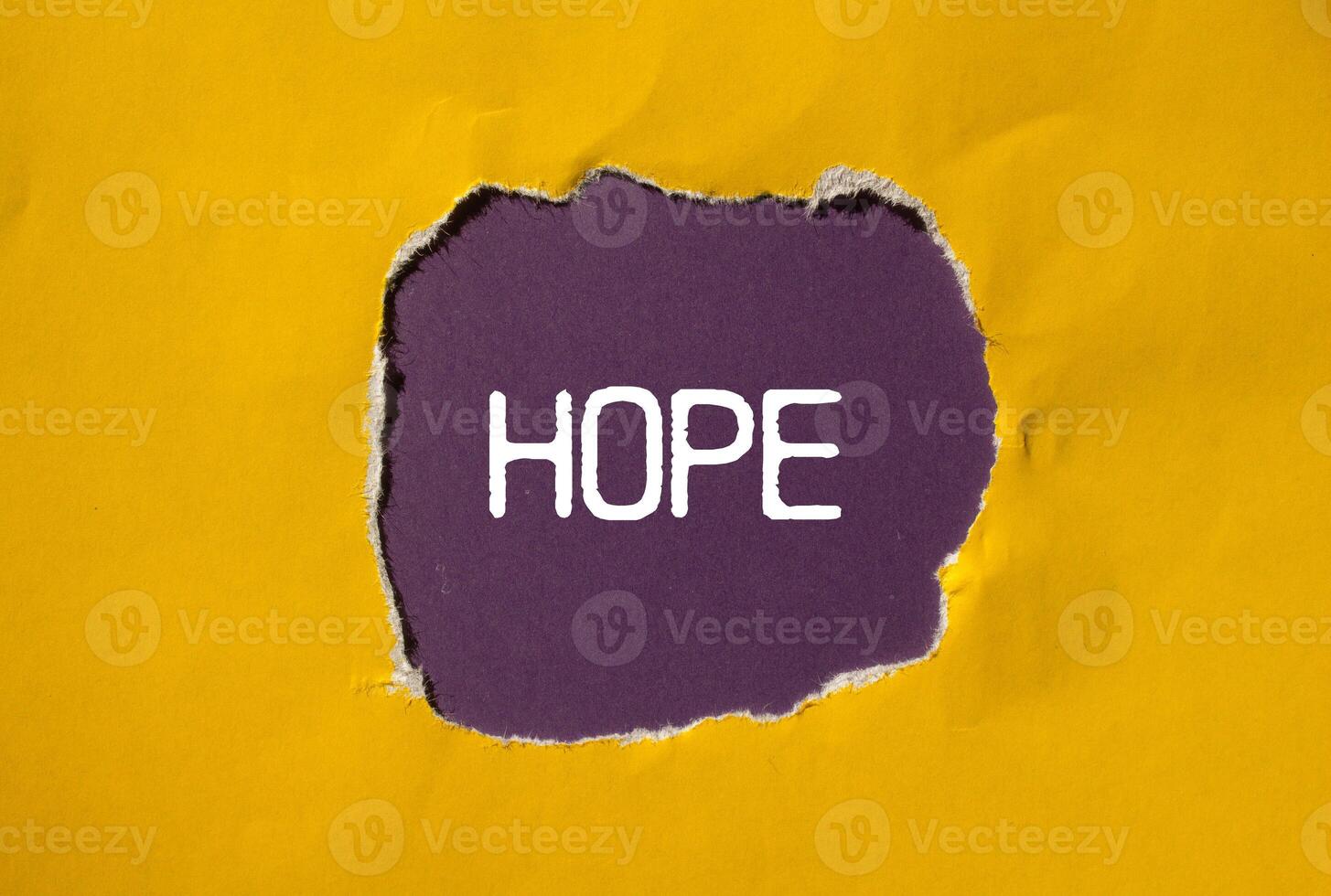 Hope message written on ripped torn yellow paper with purple background. Conceptual hope symbol. Copy space. photo
