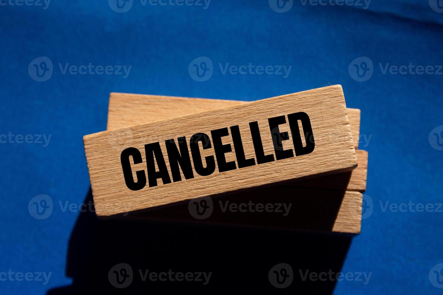 Cancelled message written on wooden blocks with blue background. Conceptual cancelled symbol. Copy space. photo