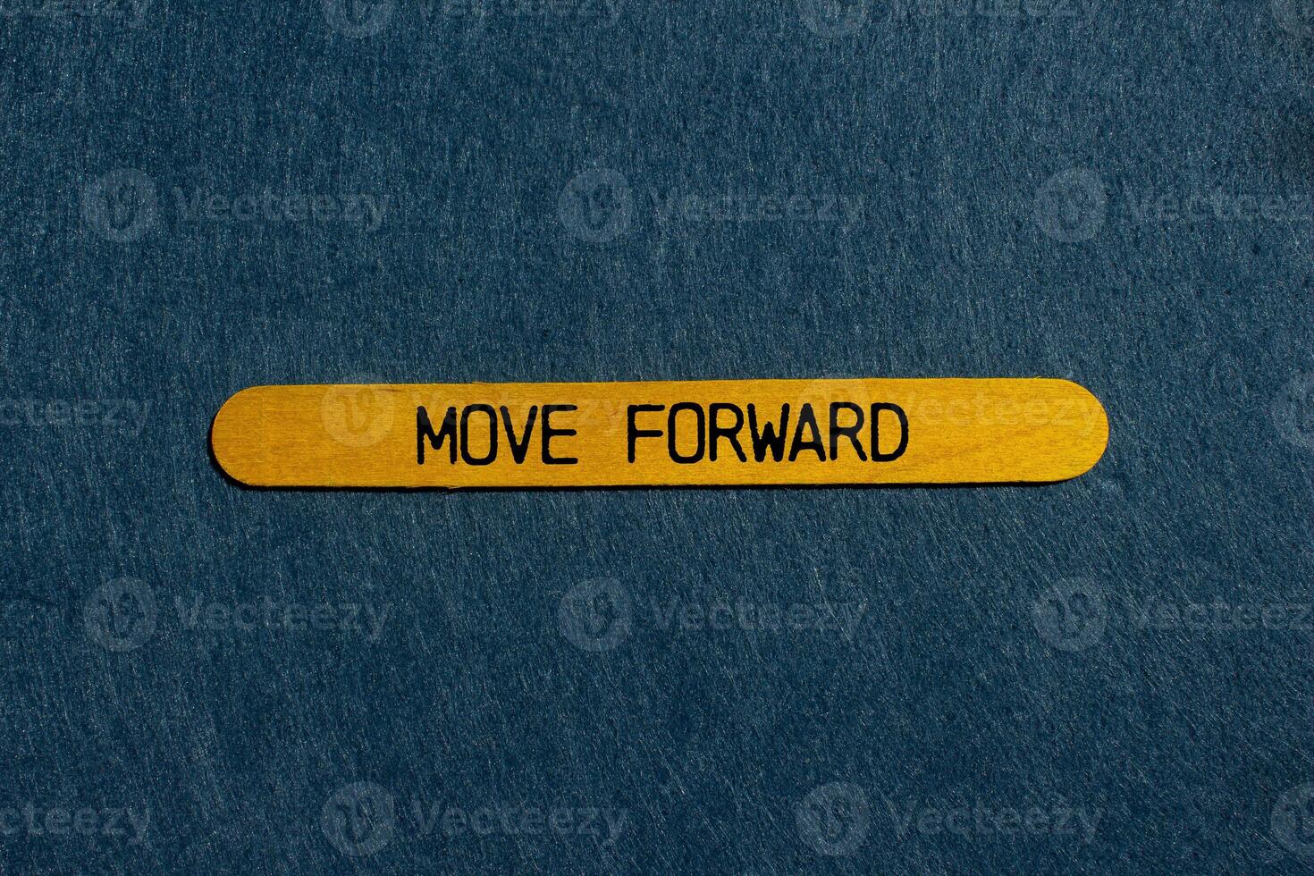 Move forward message written on yellow wooden stick with gray background. Conceptual move forward symbol. Copy space. photo