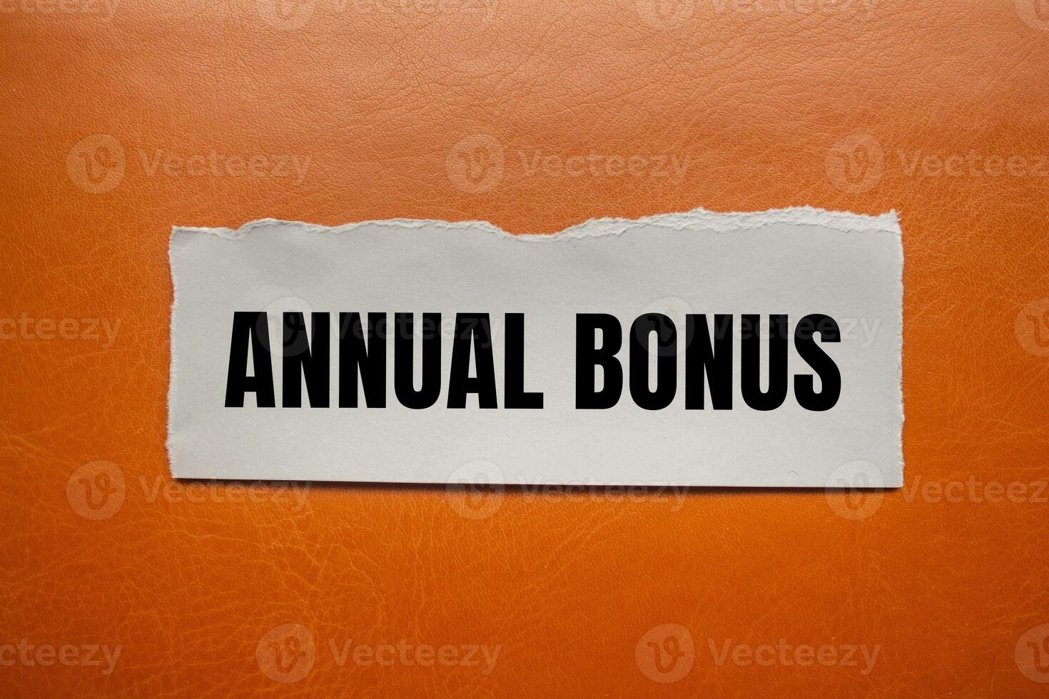 Annual bonus message written on ripped torn paper piece with brown background. Conceptual annual bonus symbol. Copy space. photo