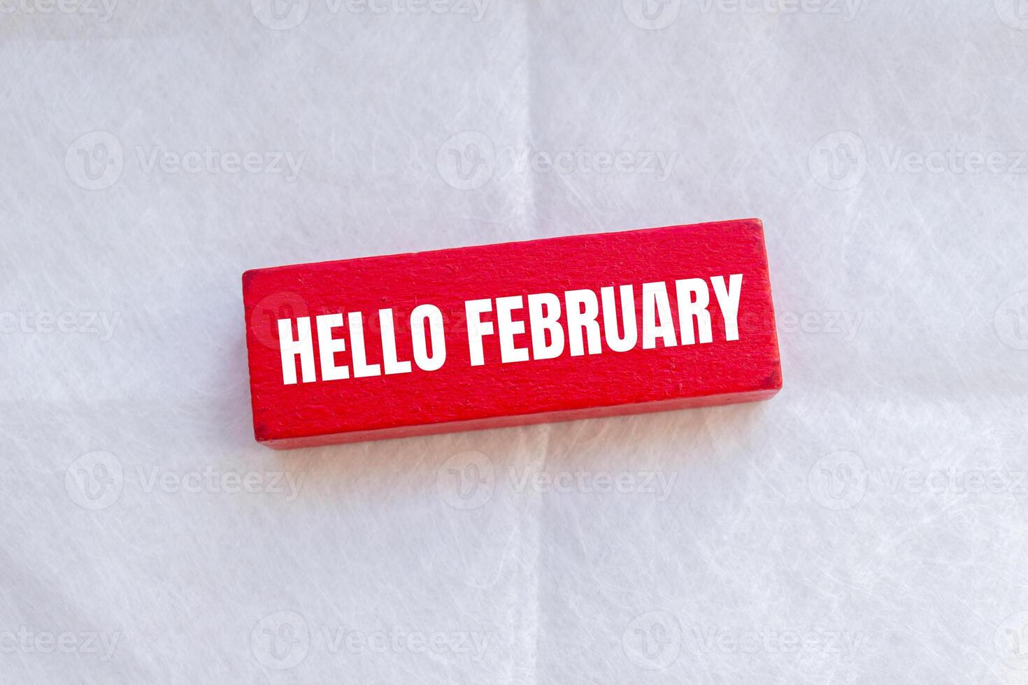 Hello february message written on wooden red block with white background. Conceptual hello february symbol. Copy space. photo