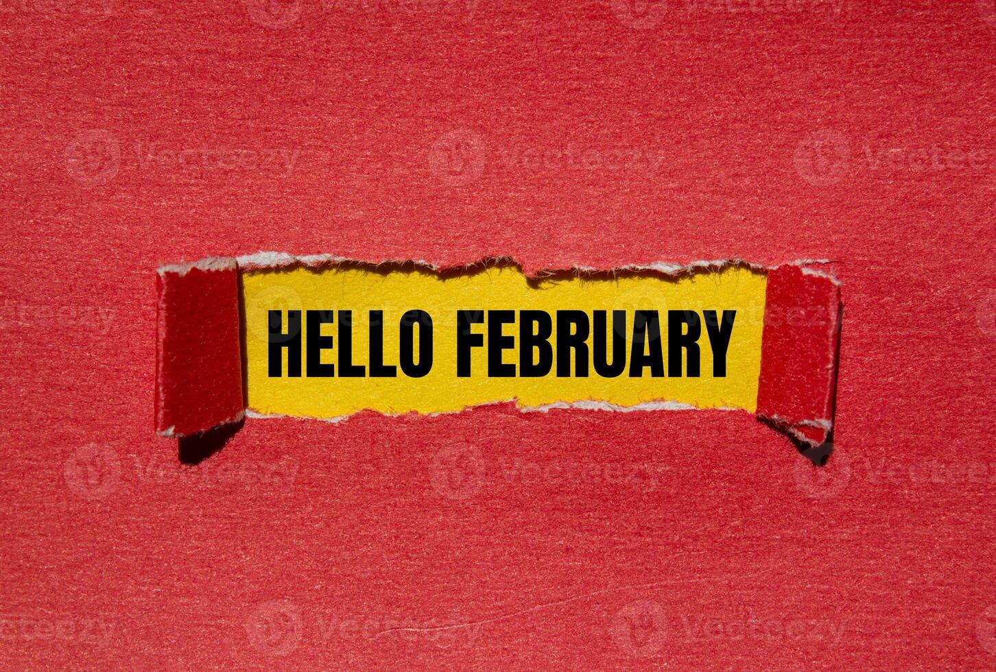 Hello february message written on ripped torn red paper with yellow background. Conceptual hello february symbol. Copy space. photo