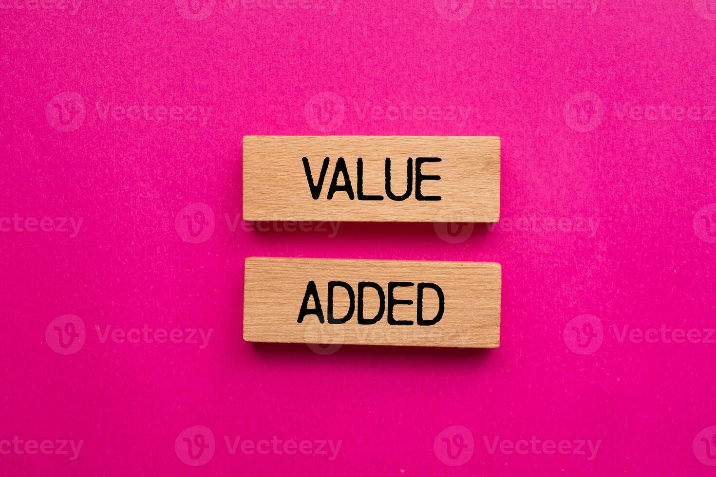 Value added message written on wooden blocks with pink background. Conceptual value added symbol. Copy space. photo