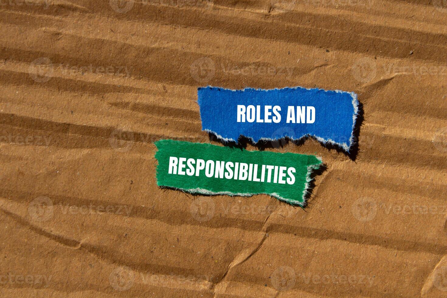 Roles and responsibilities message written on ripped torn paper pieces with cardboard background. Conceptual roles and responsibilities symbol. Copy space. photo
