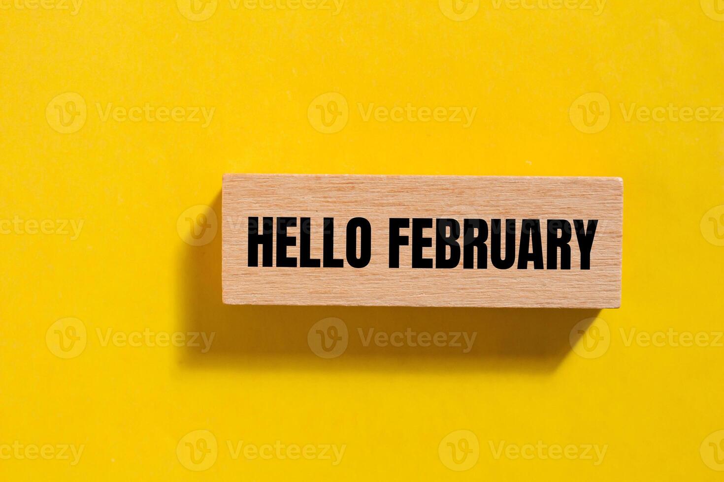 Hello february message written on wooden block with yellow background. Conceptual hello february symbol. Copy space. photo
