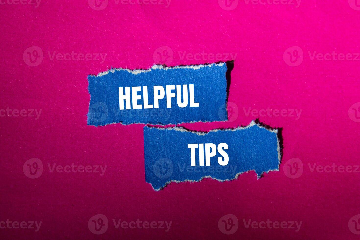 Helpful tips message written on ripped torn blue paper pieces with pink background. Conceptual helpful tips symbol. Copy space. photo