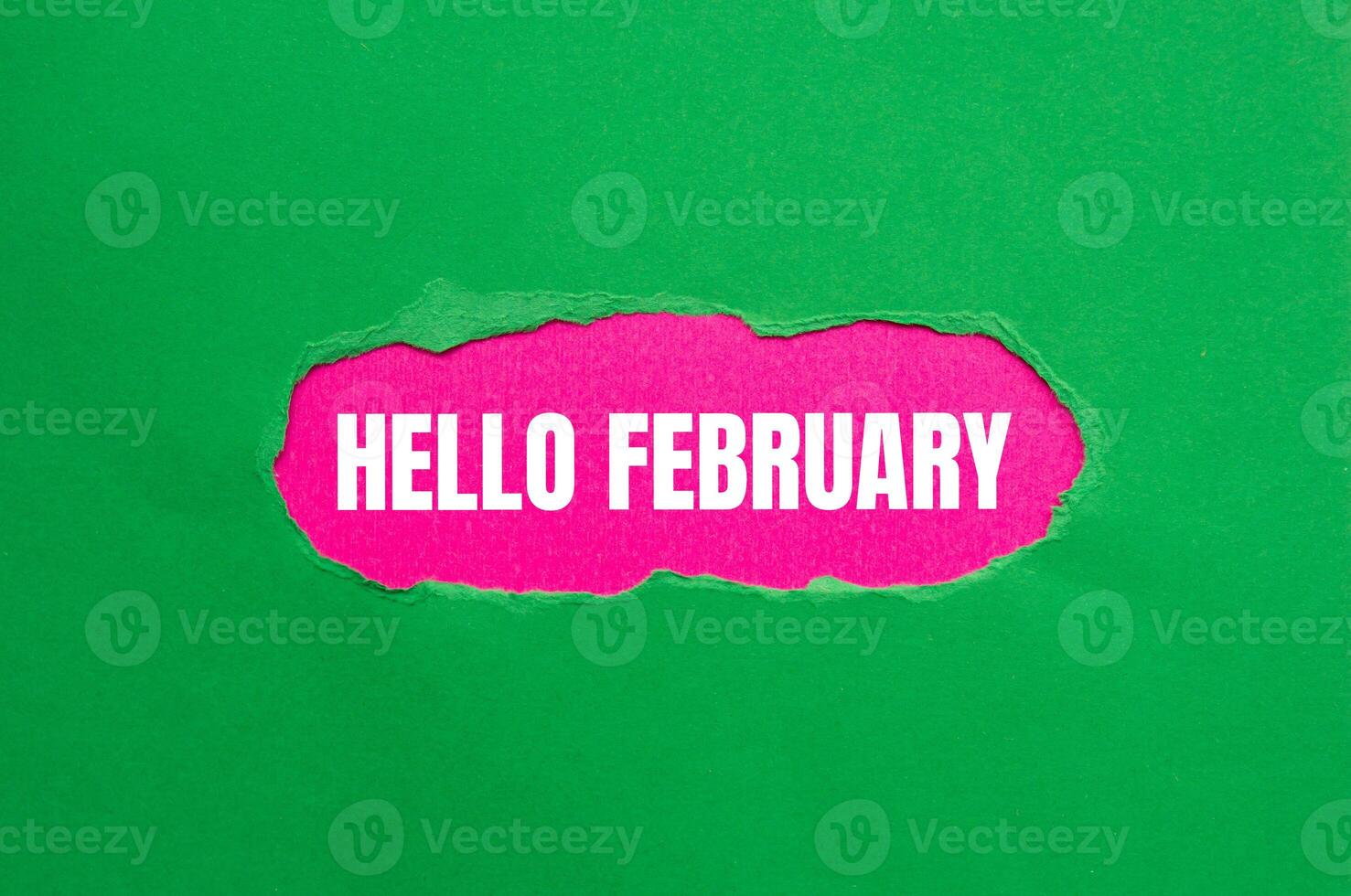 Hello february message written on ripped torn green paper with pink background. Conceptual hello february symbol. Copy space. photo