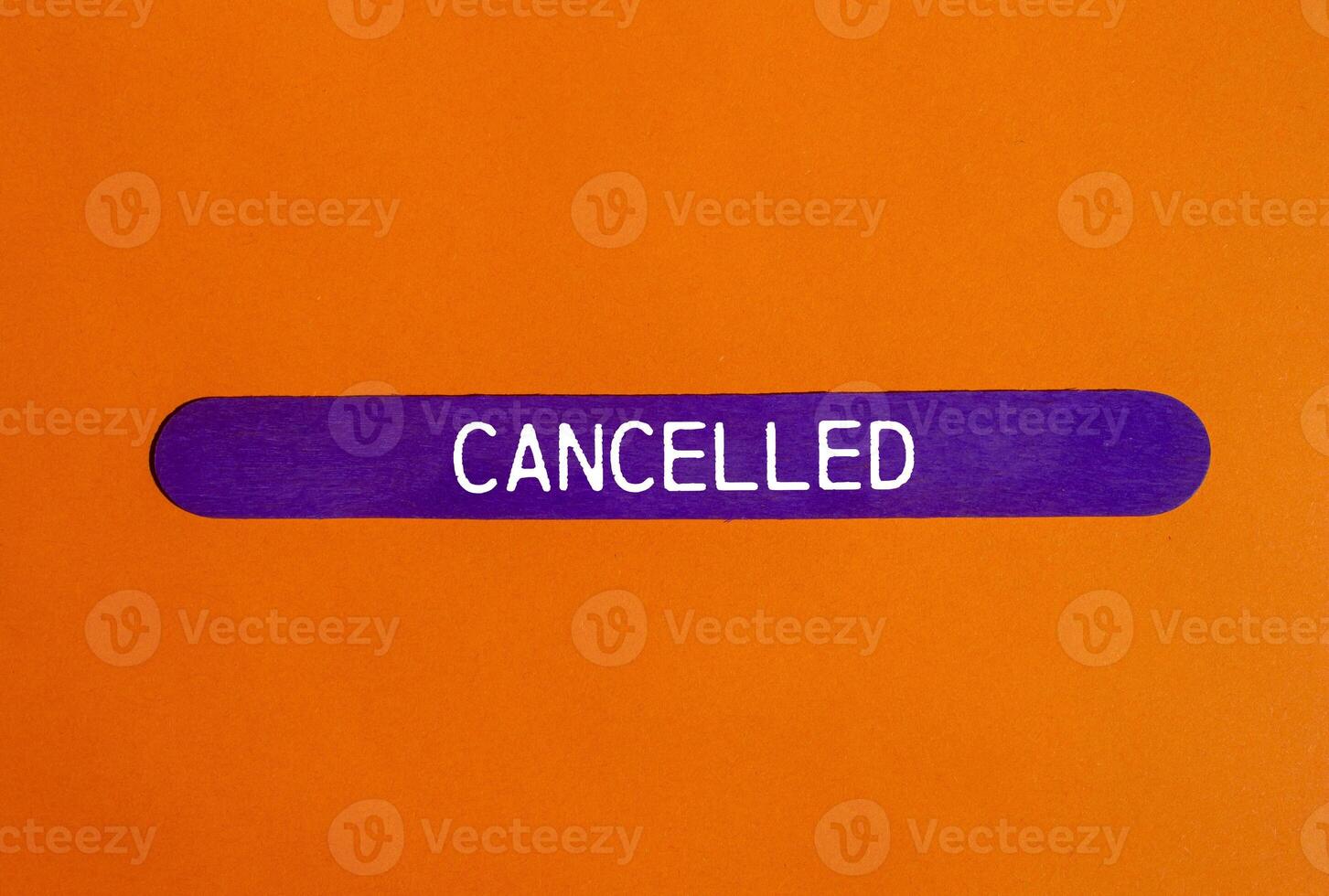 Cancelled message written on purple wooden stick with orange background. Conceptual cancelled symbol. Copy space. photo