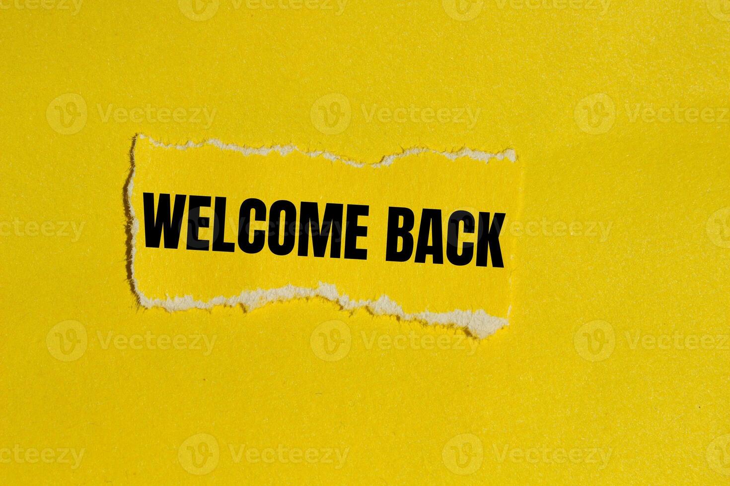 Welcome back message written on ripped yellow torn paper piece with yellow background. Conceptual welcome back symbol. Copy space. photo