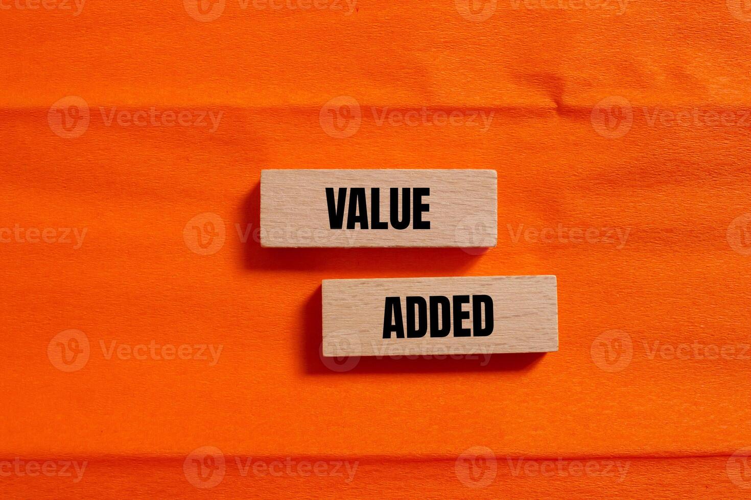 Value added message written on wooden blocks with orange background. Conceptual value added symbol. Copy space. photo