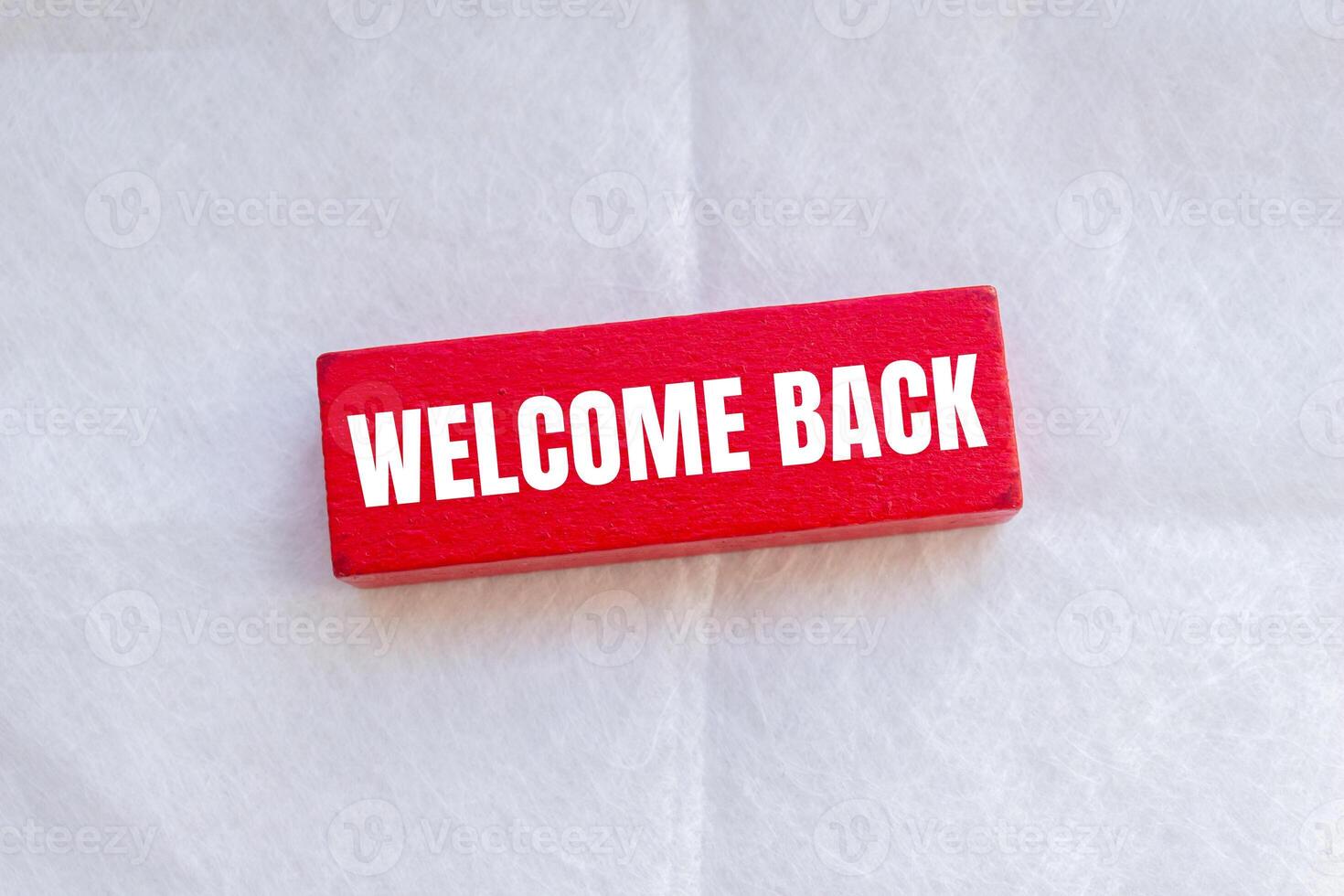 Welcome back message written on wooden red block with white background. Conceptual welcome back symbol. Copy space. photo