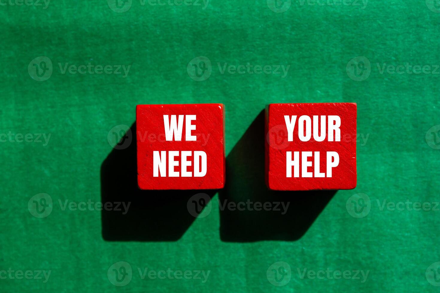 We need your help message written on red wooden cubes with green background. Conceptual we need your help symbol. Copy space. photo