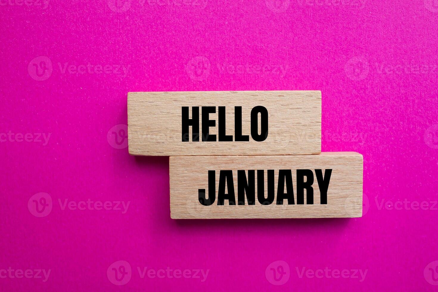 Hello january message written on wooden blocks with pink background. Conceptual hello january symbol. Copy space. photo