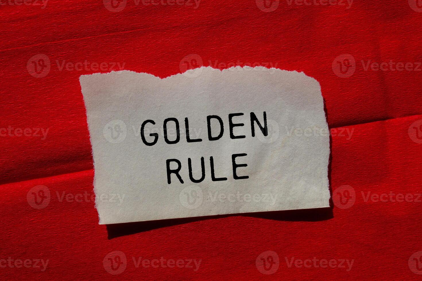 Golden rule message written on ripped torn paper piece on red background. Conceptual golden rule symbol. Copy space. photo