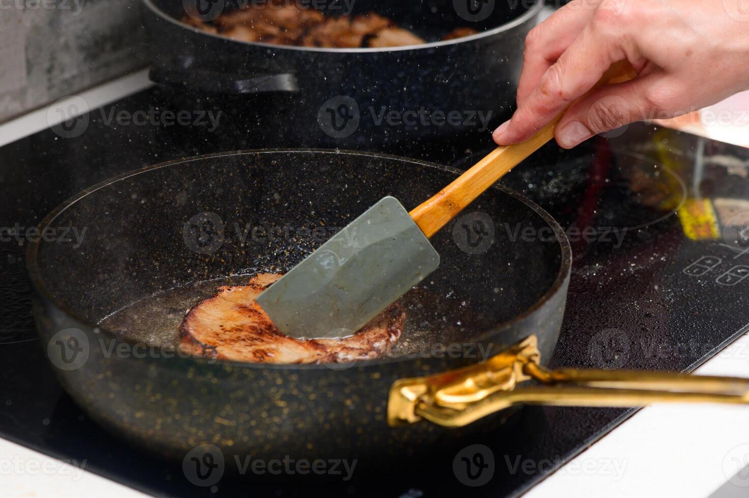 Cooking deliciously golden-brown pork chops on a stovetop using a spatula photo