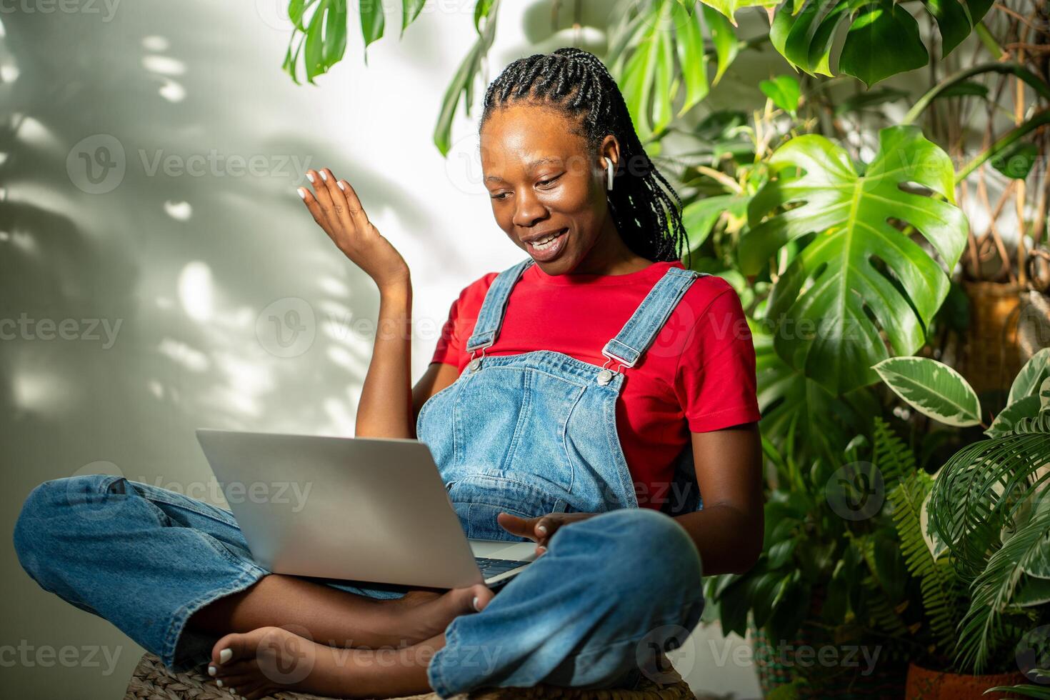 Interested black woman with laptop have call on knees in earphones gestures with hand, talking photo