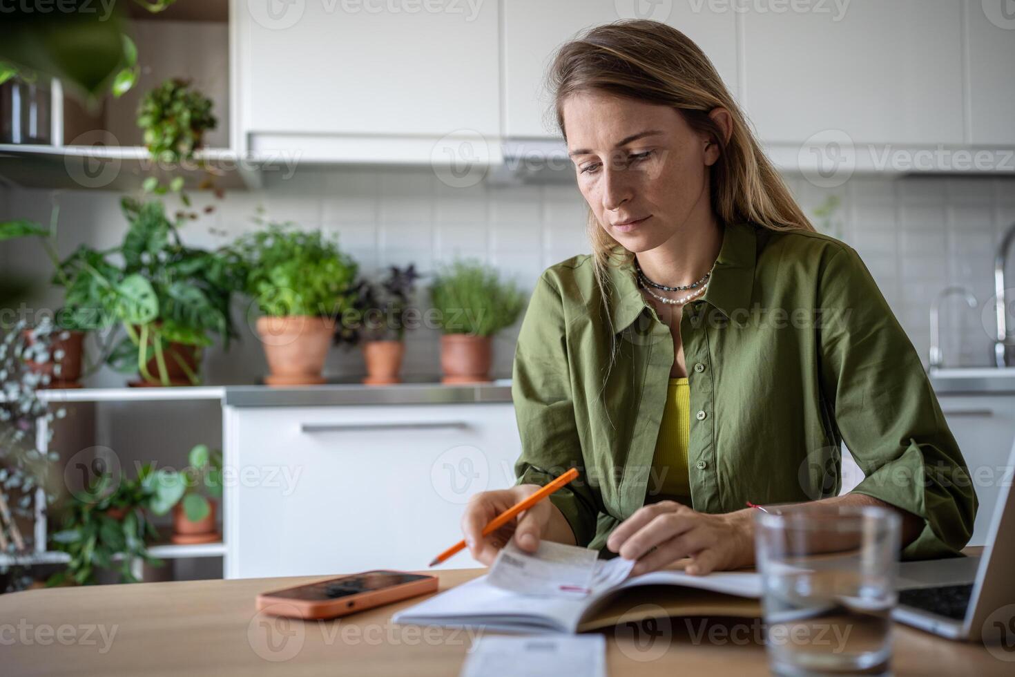 Focused woman attentive budget sitting at table write down expenses in notebook use phone calculator photo