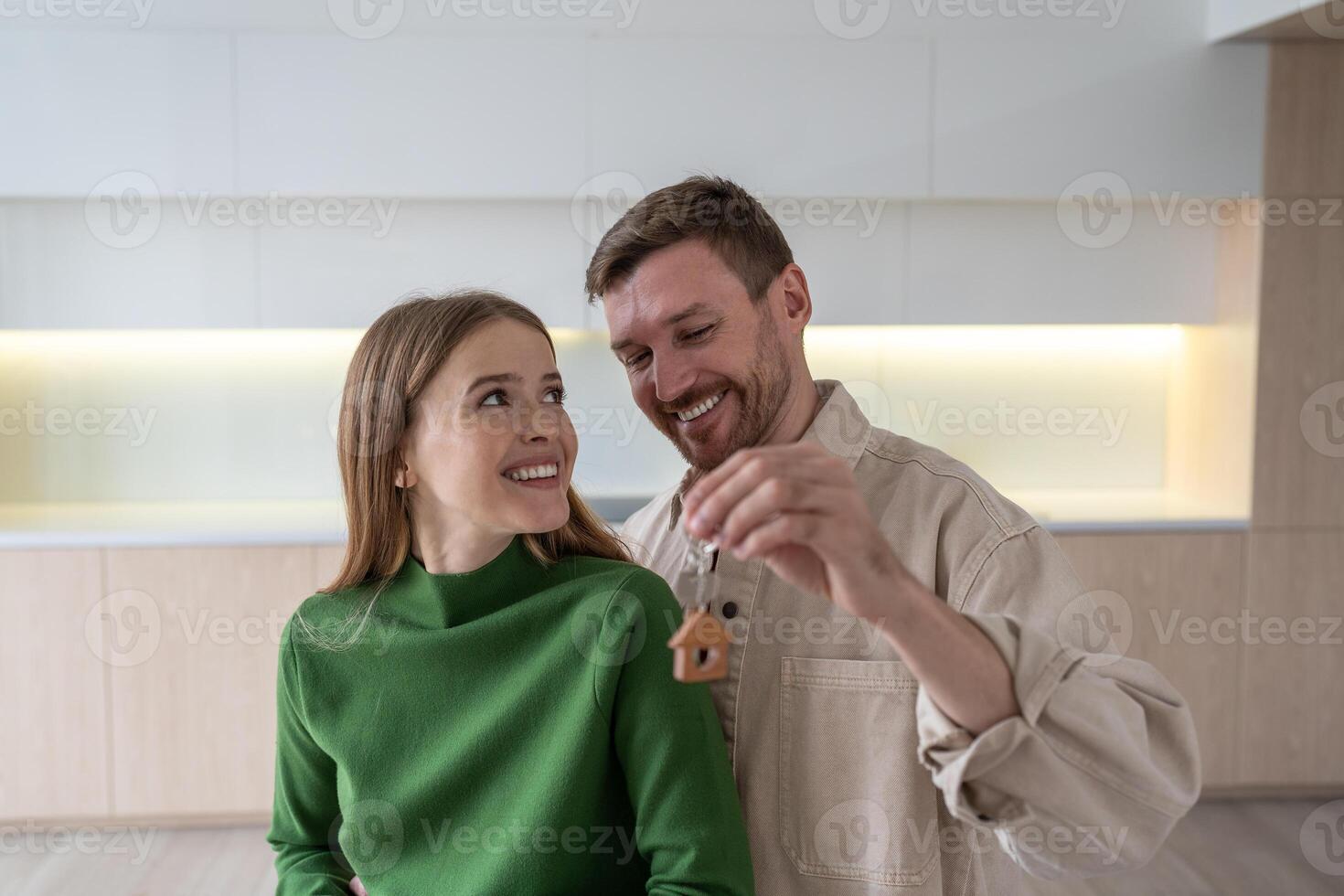 Glad smiling family hugging with keys to new apartment after moving in, celebrating new real estate photo