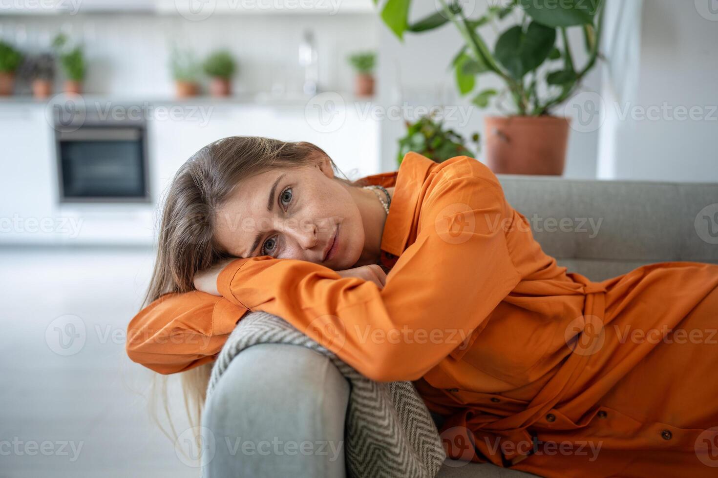 Portrait of relaxed woman lying on sofa with head bowed on armrest look at camera with calm emotion. photo