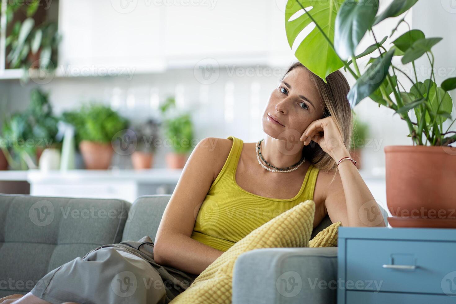 Portrait of woman on sofa among plants looking at camera with calm confident sure expression on face photo