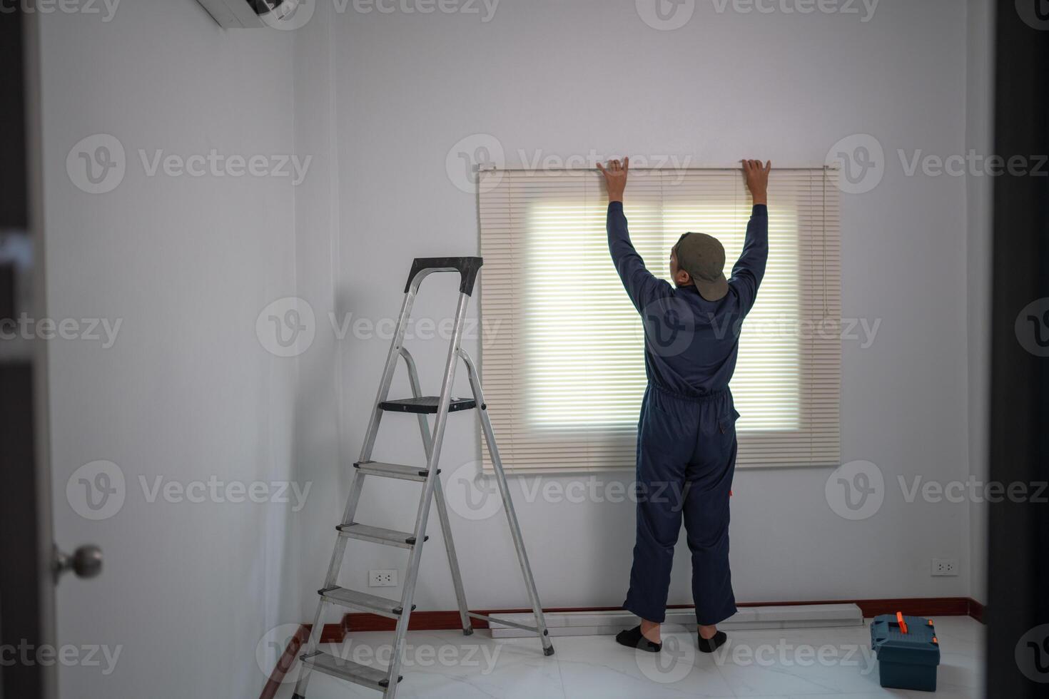 Worker Setting Up Window Blinds with Ladder and Toolbox in Minimalist Room photo