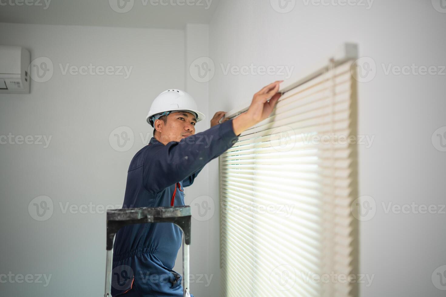 Worker with Hard Hat Installing Window Blinds in Residential Interior photo
