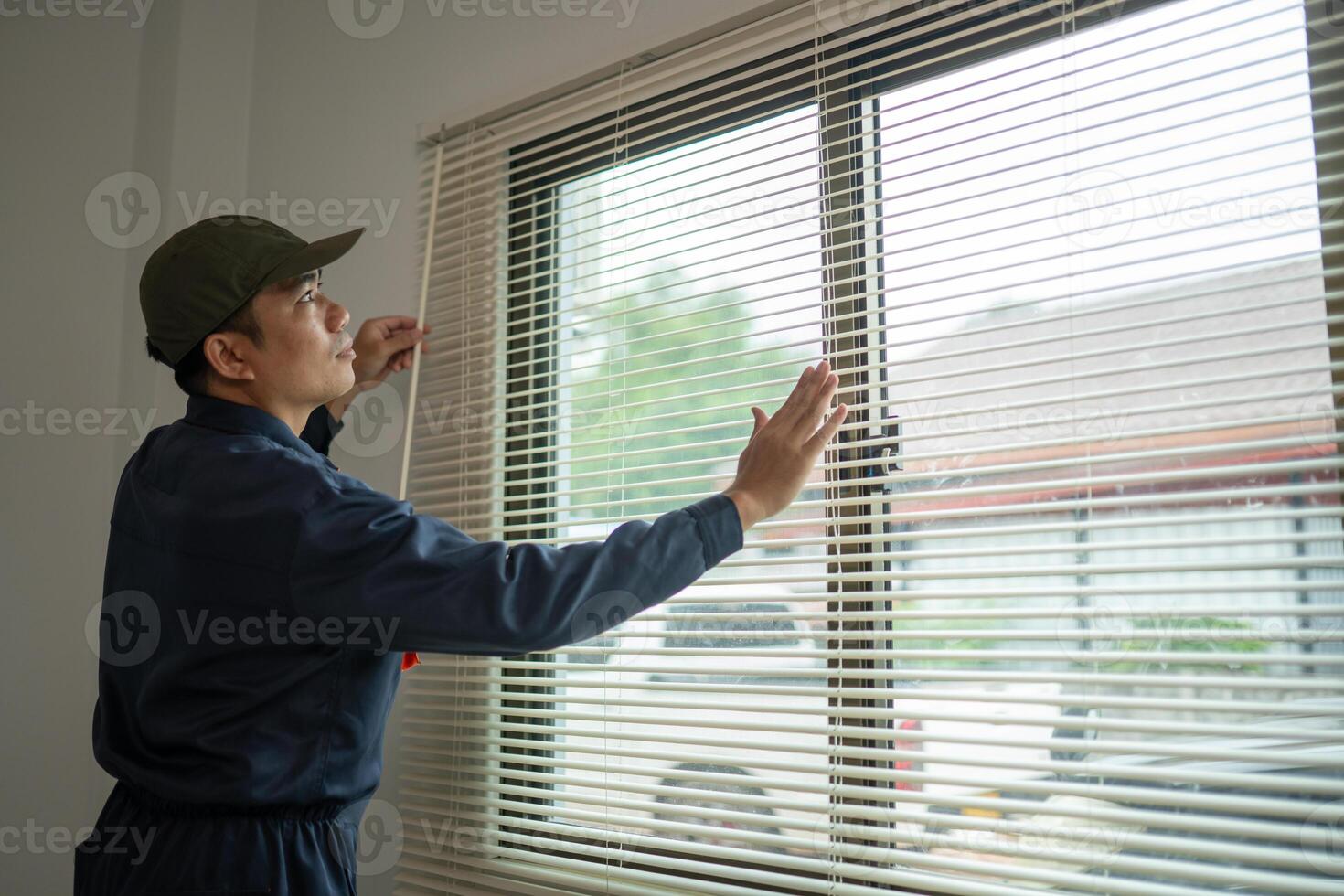 Worker Adjusting Window Blinds with Natural Light in Modern Interior photo