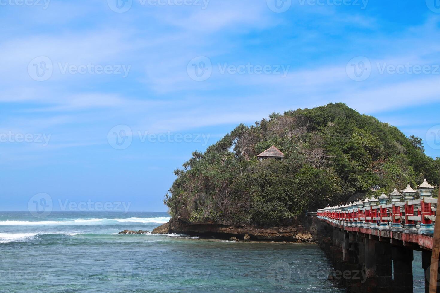 Balekambang Beach on a sunny day with bright blue skies and Ismoyo Island visible in the distance photo