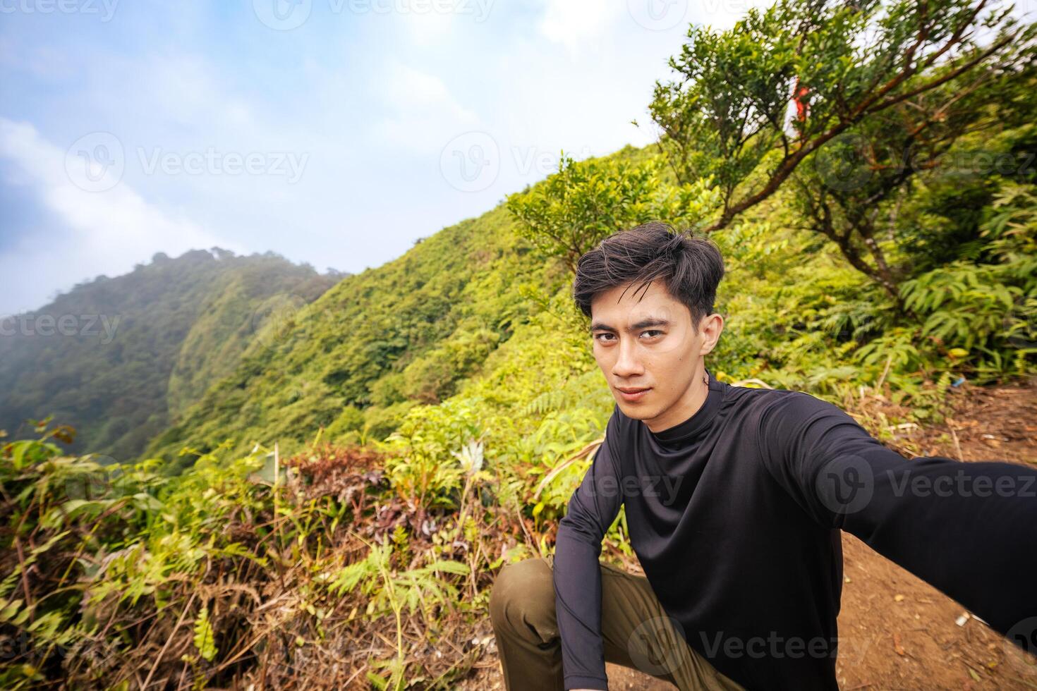 Man in the Wilderness, Posing Proudly on Mountain Peak. Serene Nature View from the Top of the Mountain. photo